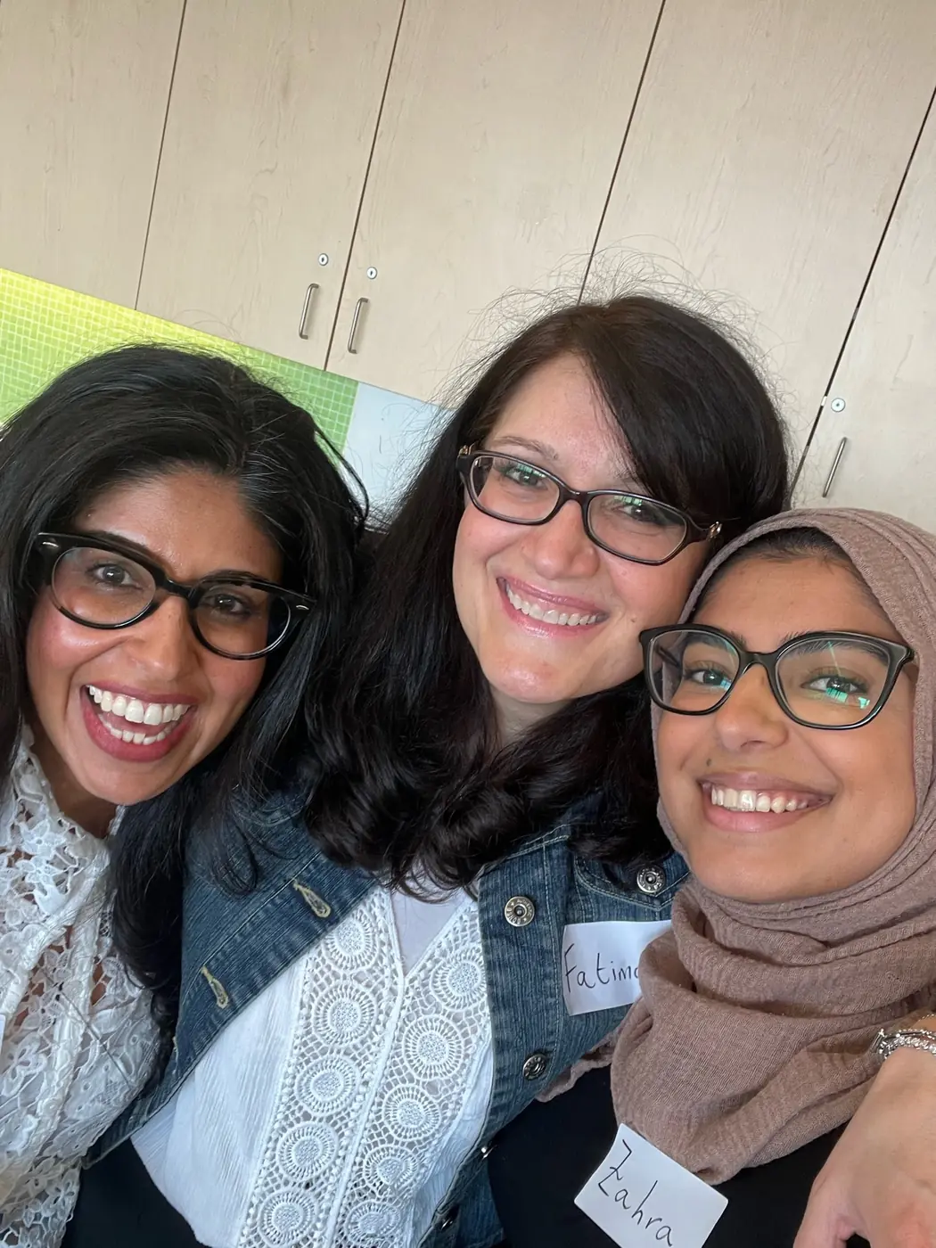 Three smiling women taking a selfie together at a humanKIND event