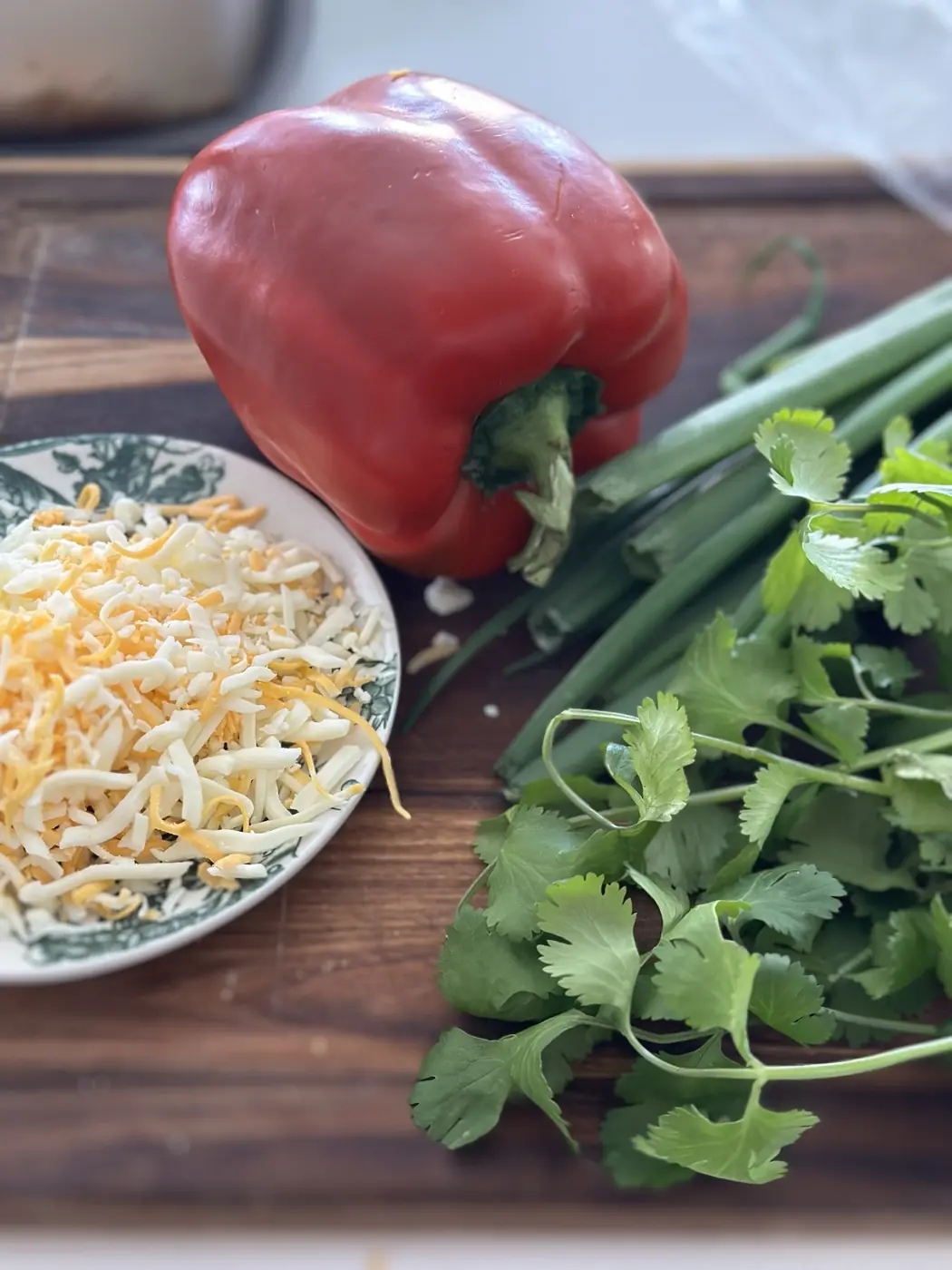 A red pepper, fresh herbs and shredded cheese ready for a cooking demo