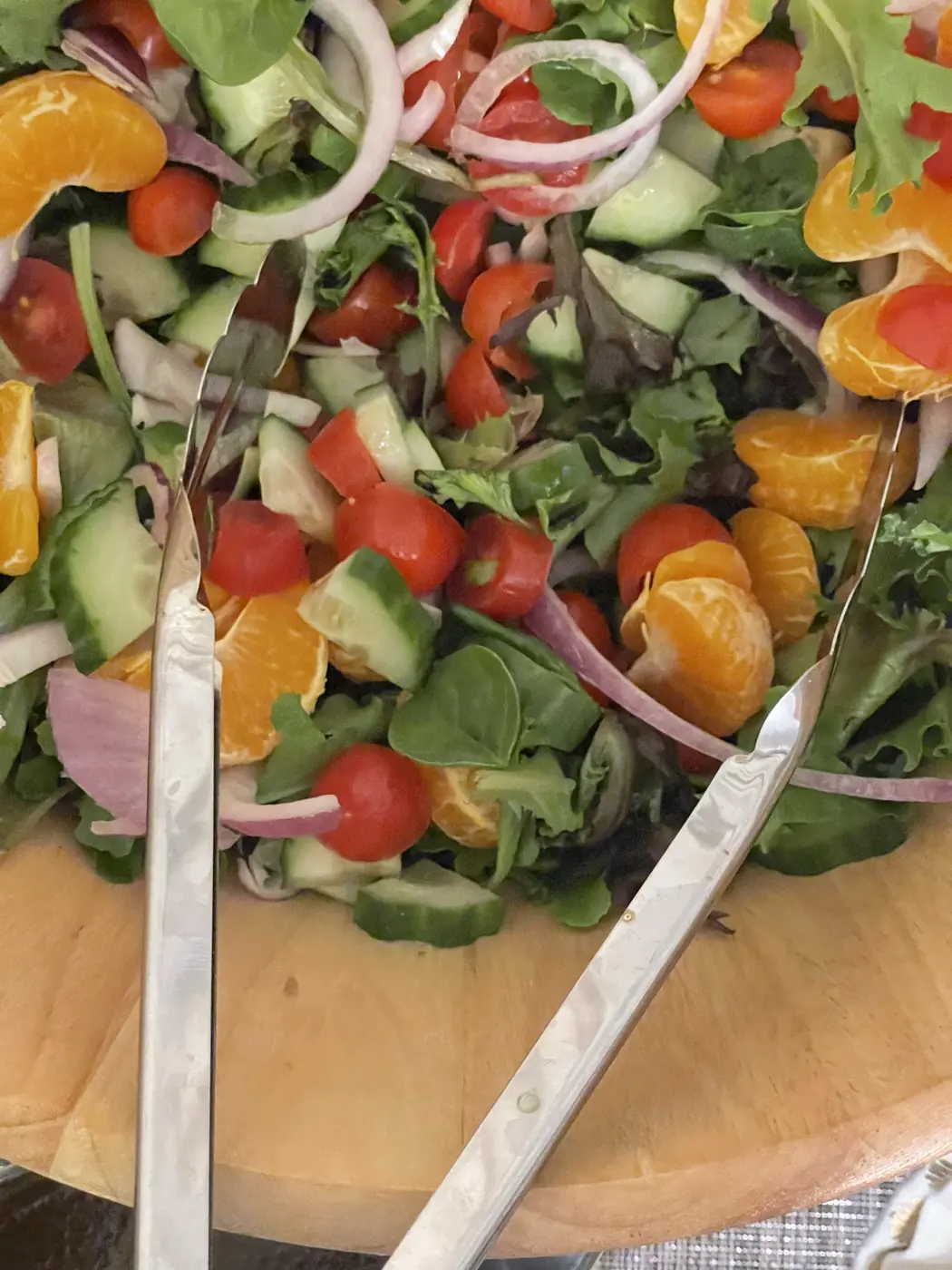 A large bowl of fresh salad with oranges, tomatoes and red onion