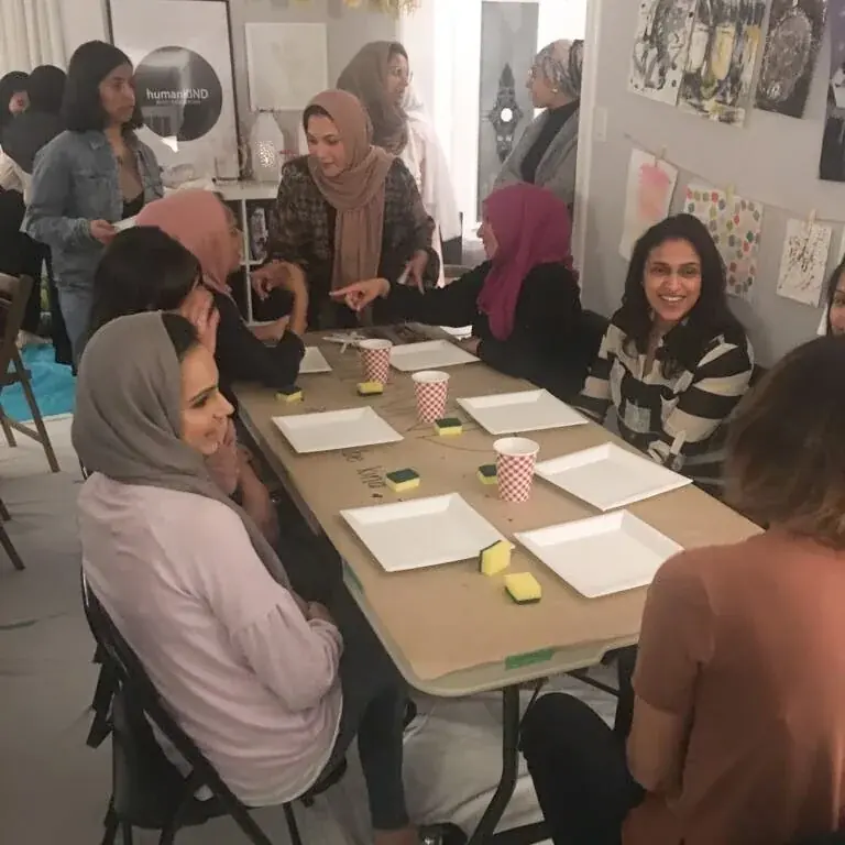 Women seated around a long table during the painting workshop