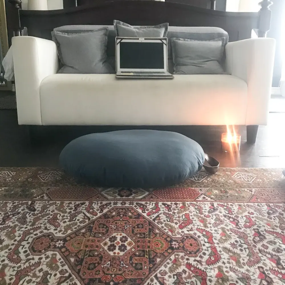 A floor cushion and candle on a patterned rug