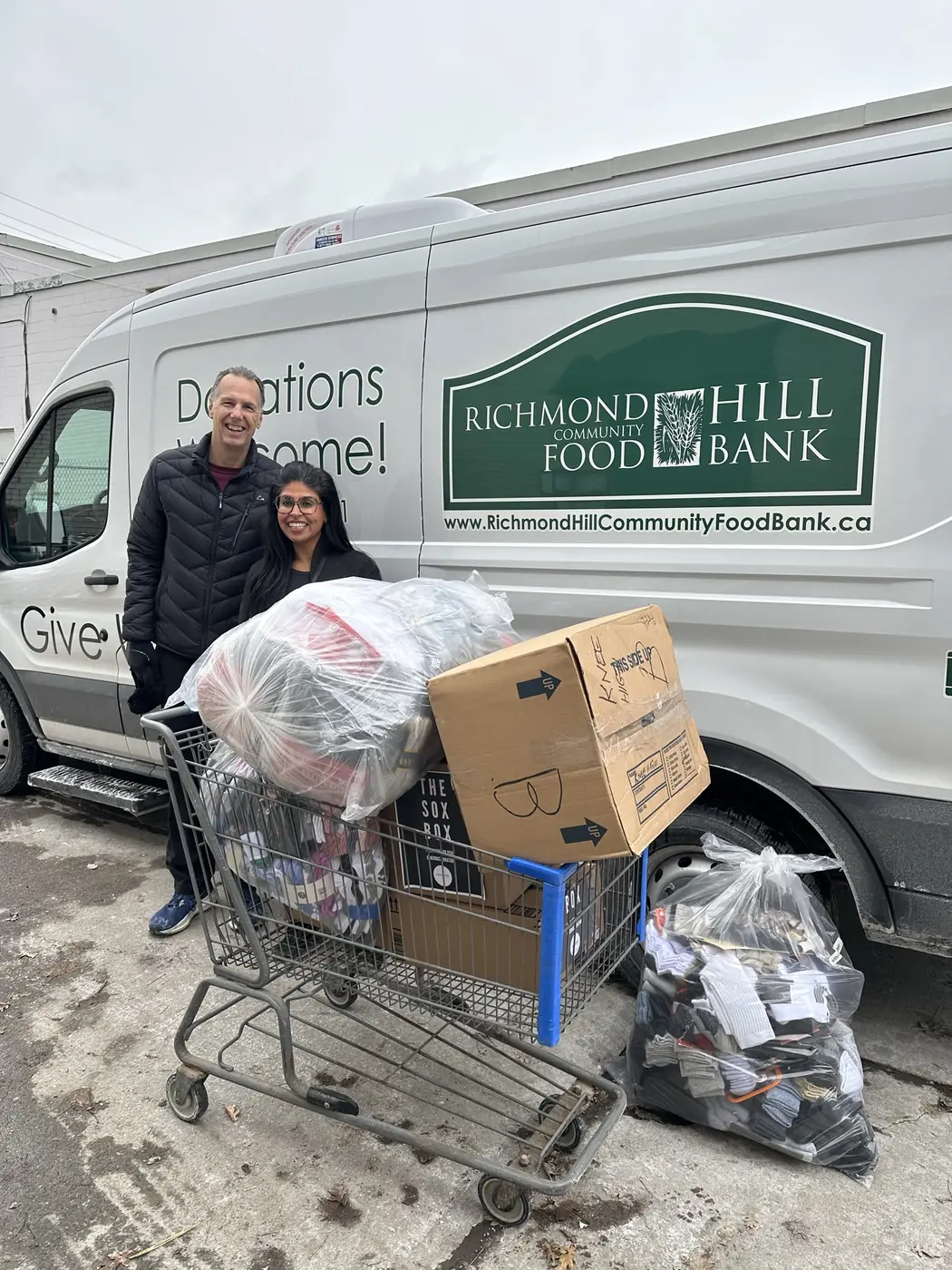 Bags of donated socks loaded into a cart beside a community food bank van