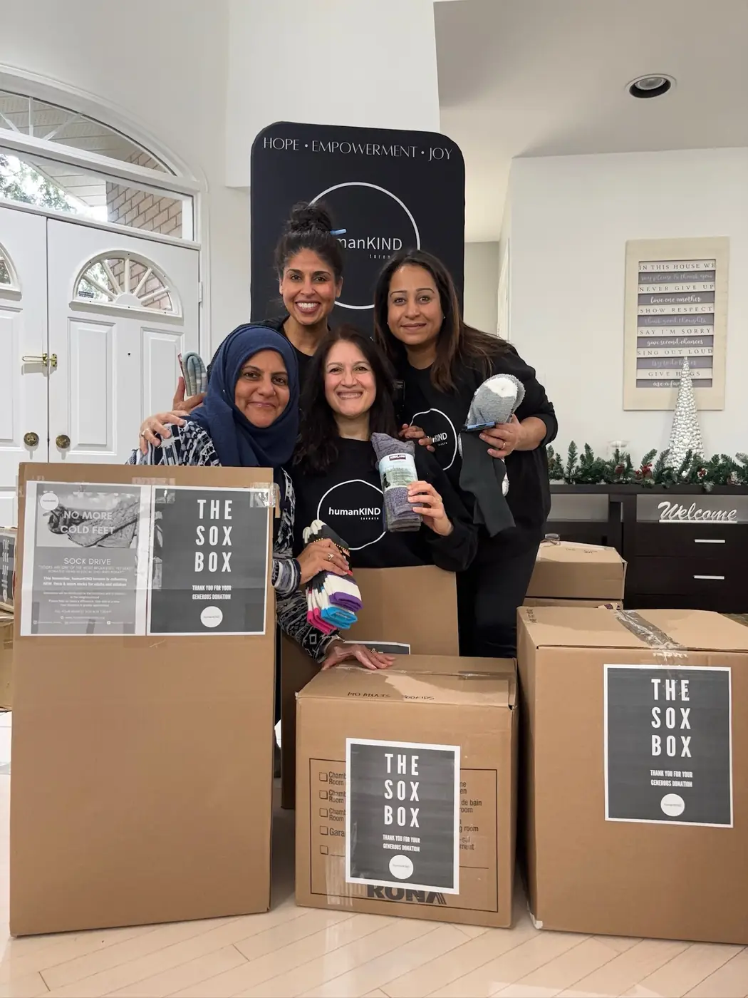 Volunteers surrounded by Sox Box collection boxes filled with new socks