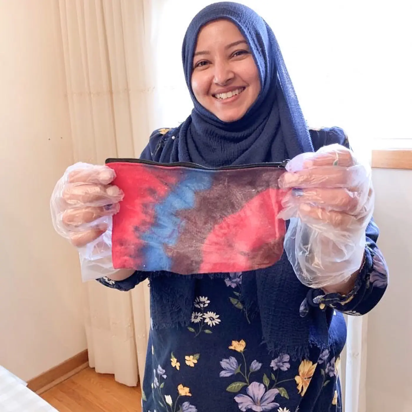 A smiling volunteer holding up a hand-dyed pouch she made